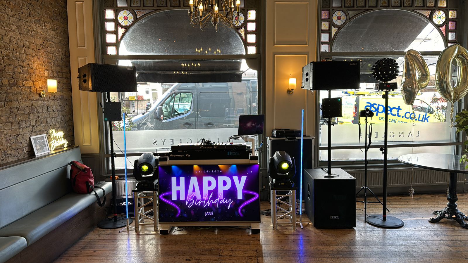DJ booth with light-up HAPPY sign and speakers set up for a birthday party