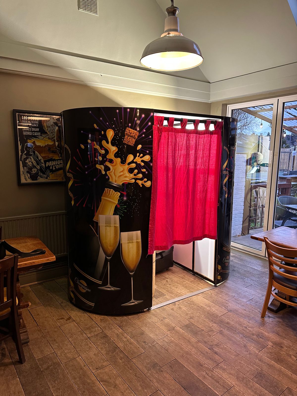 Enclosed champagne-themed photo booth with red curtain