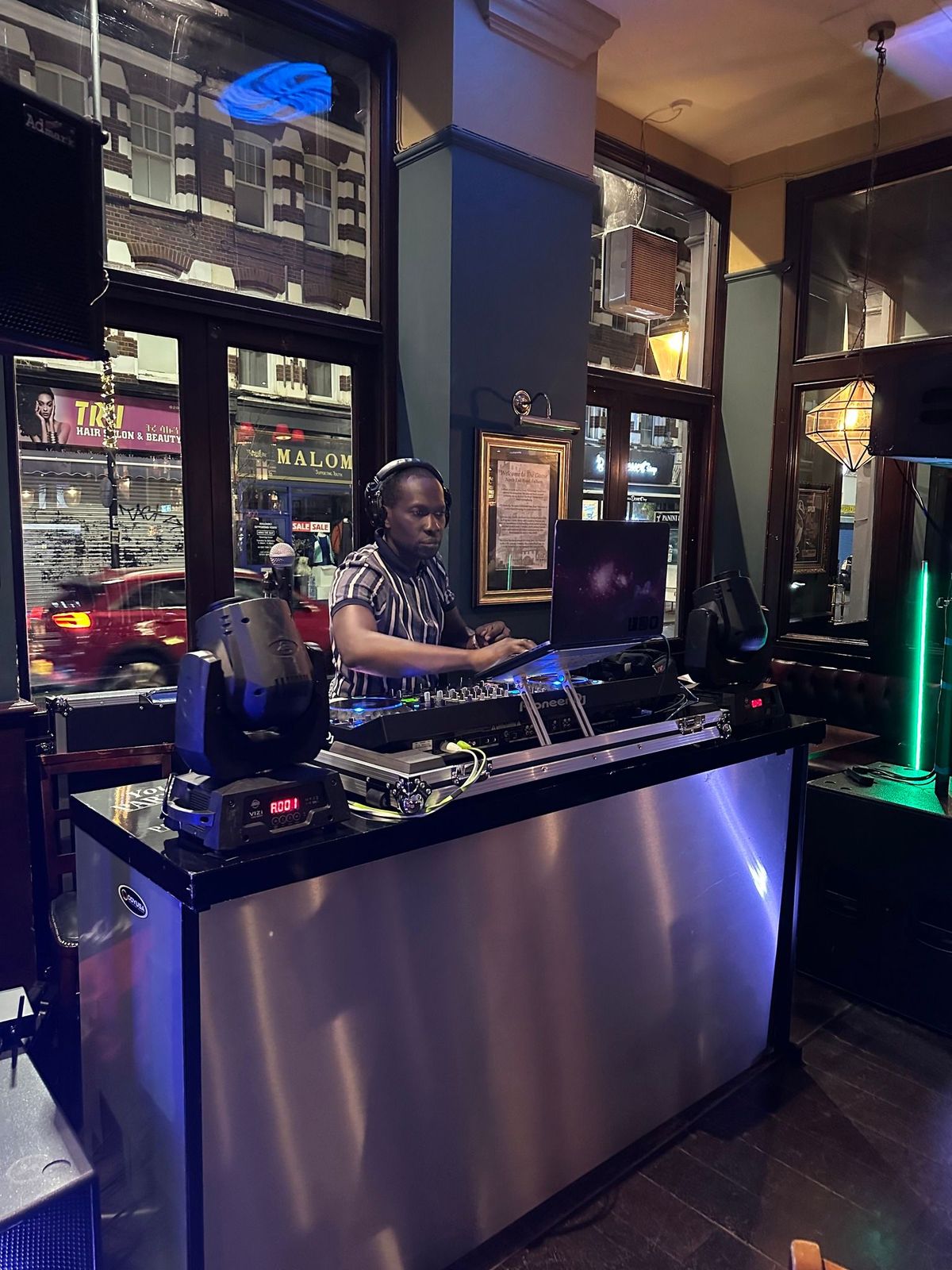 Dyson Events DJ mixing behind a silver DJ booth at a bar venue