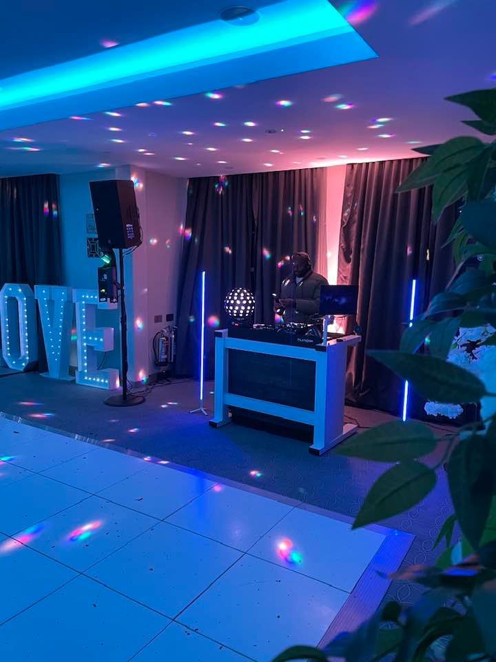 Illuminated LOVE letters beside a white DJ booth under blue uplighting