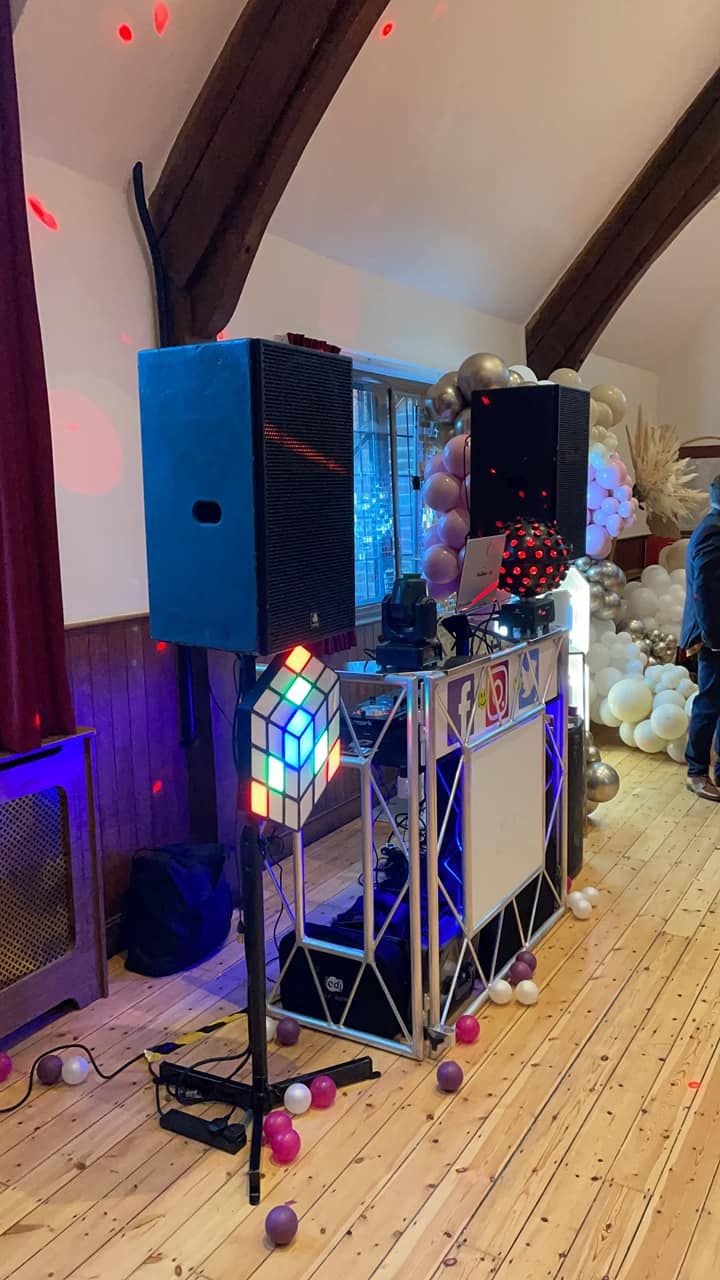 Party DJ setup with speakers and lighting beside balloon decorations
