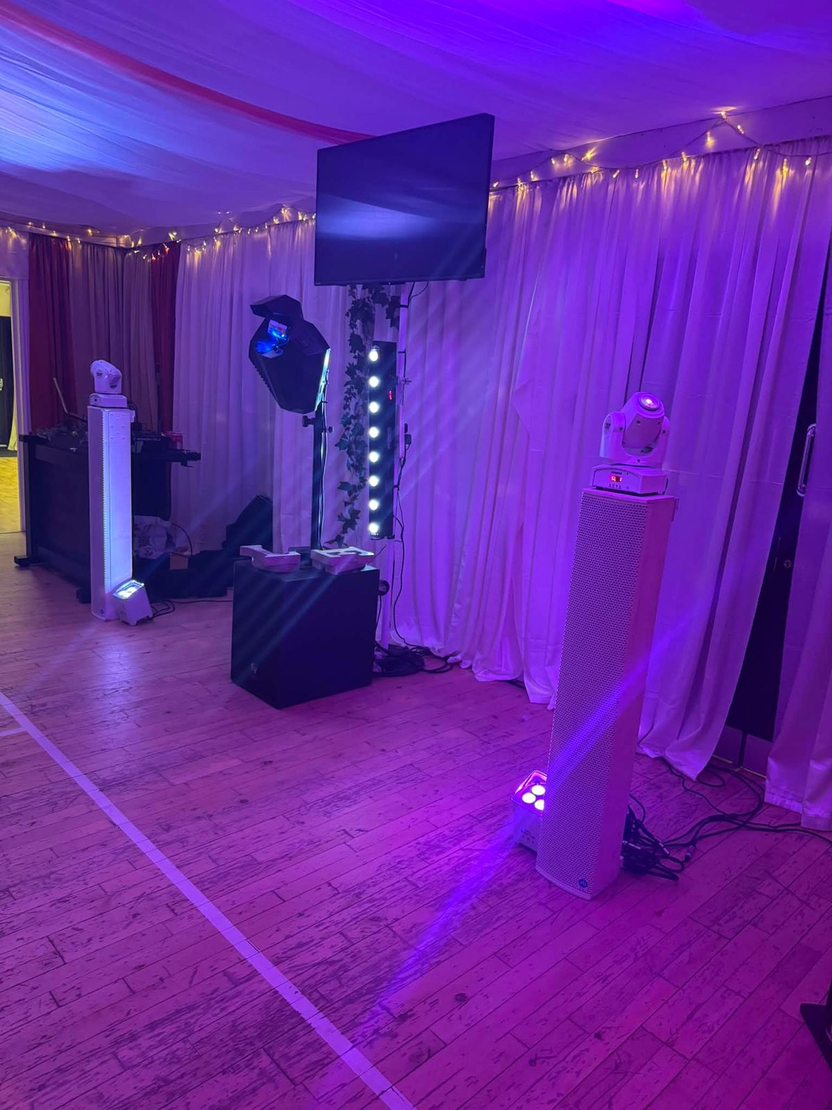 Function room washed in purple uplighting with moving-head lights